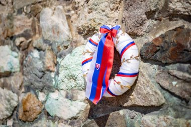 Taş duvarında Slovak bayrağı olan bir çelenk.