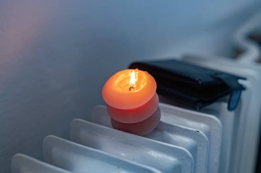 Yanan bir mum, radyatör ve bir cüzdan. Ukrayna 'daki savaş nedeniyle ısıtma fiyatları artıyor.