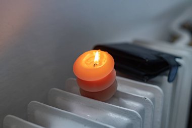 Yanan bir mum, radyatör ve bir cüzdan. Ukrayna 'daki savaş nedeniyle ısıtma fiyatları artıyor.