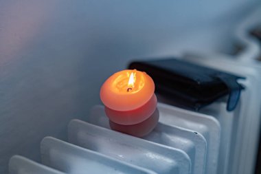 Yanan bir mum, radyatör ve bir cüzdan. Ukrayna 'daki savaş nedeniyle ısıtma fiyatları artıyor.