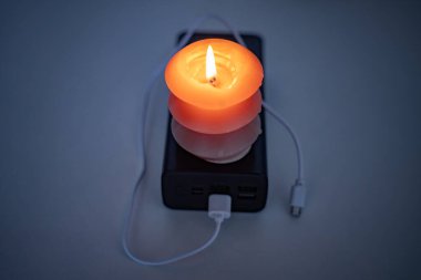 Yanan bir mum ve bir güç bankası. Ukrayna 'daki savaş nedeniyle elektrik kesintileri.