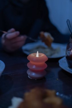 Masadaki yemeğin yanında yanan bir mum. Ukrayna 'daki savaş nedeniyle elektrik kesintileri.