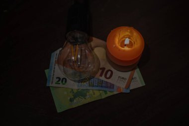 Banknotların üzerinde yanan bir mum ve fişi çekilmiş bir lamba var. Ukrayna 'daki savaş nedeniyle elektrik kesintileri.
