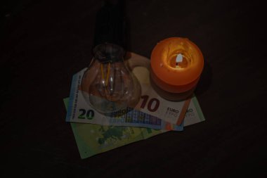 Banknotların üzerinde yanan bir mum ve fişi çekilmiş bir lamba var. Ukrayna 'daki savaş nedeniyle elektrik kesintileri.