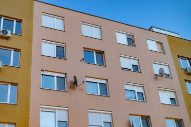 Pencereleri ve panjurları olan tipik bir apartman tipi.