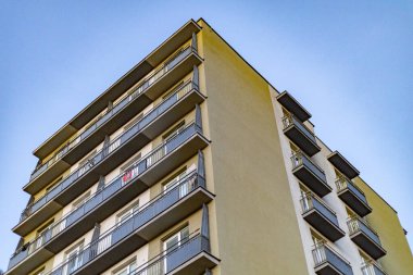 Mavi gökyüzüne karşı geometrik balkonları olan modern apartman dairesi.