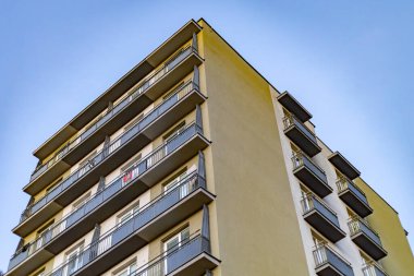 Mavi gökyüzüne karşı geometrik balkonları olan modern apartman dairesi.