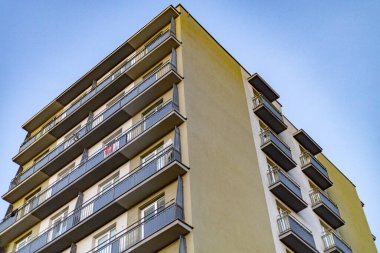Mavi gökyüzüne karşı geometrik balkonları olan modern apartman dairesi.