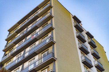 Mavi gökyüzüne karşı geometrik balkonları olan modern apartman dairesi.