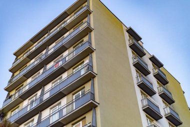 Mavi gökyüzüne karşı geometrik balkonları olan modern apartman dairesi.