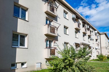 Evin dış tarafında küçük balkonları ve yeşil çimenleri olan bir apartman dairesi.