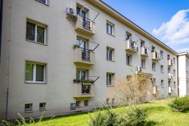 Küçük balkonları ve mavi gökyüzü olan modern apartman binası.