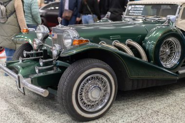Bir otomobil fuarında krom detaylarıyla zümrüt yeşili, klasik, antika bir arabanın yakın çekimi.