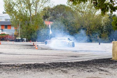 Adrenalin sürüklenme savaşı: asfalt yolda lastik dumanı ile kayan spor arabalar