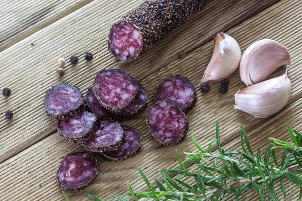 Fette di salame con pepari su un tavolo di legno — Foto Stock