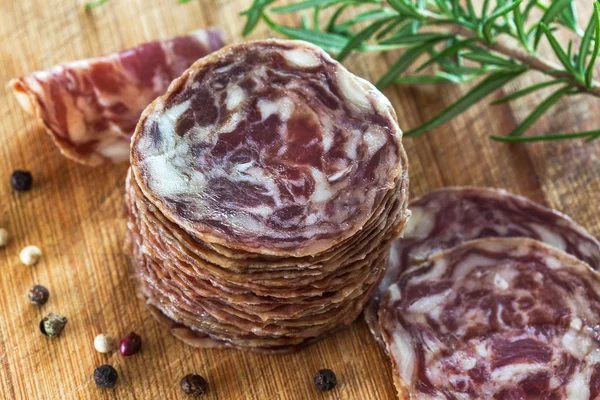 Rebanadas de salami con compañeros en una mesa de madera —  Fotos de Stock