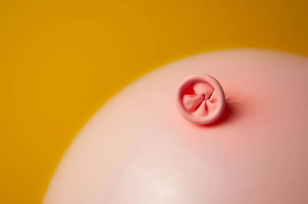 An image of a pink balloon on a yellow background. Metaphor anus, proctology, bowel health. — ストック写真