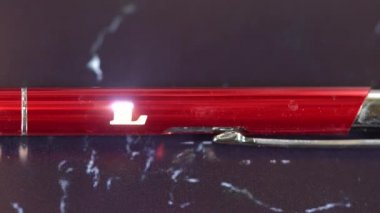 Kırmızı metal bir kaleme lazer oyması. Modern endüstriyel teknolojiler. Kelime Aşk