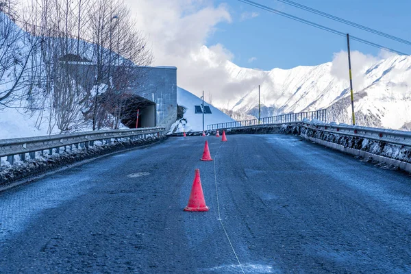 Road asphalt  work in winter mountains. Red traffic cones in the middle of the street.