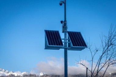Kışın dağlarda güneş panelleri olan açık hava güvenlik kamerası.