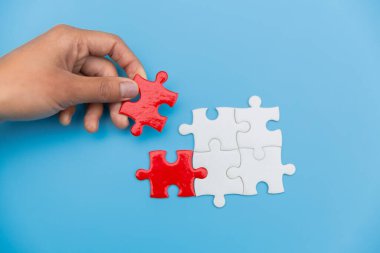 Beyaz ve kırmızı yapboz arasındaki yapboz, bir iş adamının elindeki yapboz, bir iş adamının yapboz birleştirmesi..