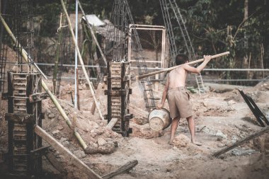 Erkek işçiler inşaat alanında çalışıyor, çocuk işçiliğine, fakir çocuklara, inşaat işine, şiddet çocuklarına ve kaçakçılık konseptine karşı.
