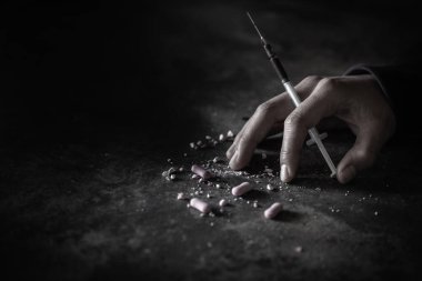 Bir uyuşturucu bağımlısının insan eli ve yerde yatan bir şırınga. Dünya Uyuşturucu Karşıtı Günü. 