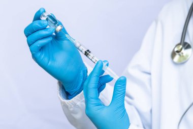 Laboratuvarda elinde sıvı aşılarla bir şırınga tutan doktor ya da bilim adamı. Covid-19 Corona virüsüne karşı kavramsal mücadele.
