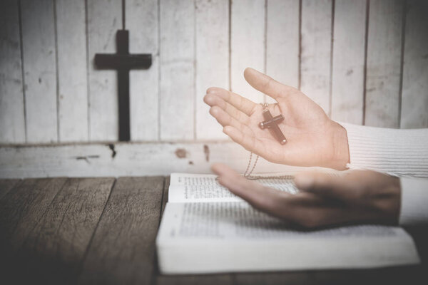 Hand of woman while praying for christian religion, Casual woman praying with a cross, Religion concept.