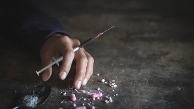 Çılgın bir uyuşturucu bağımlısı şırıngadaki ilacın başka bir dozuna uzanıyor. Bağımlı adam, uyuşturucu karşıtı konsept. Erkek uyuşturucu bağımlısı, uyuşturucu şırıngası.
