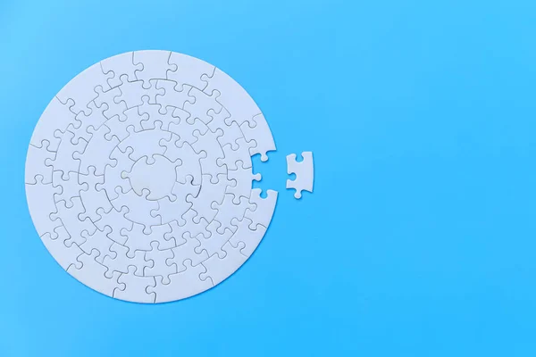 White jigsaw puzzle on a blue background. Completing final task, missing jigsaw puzzle pieces and business concept with a puzzle piece missing.