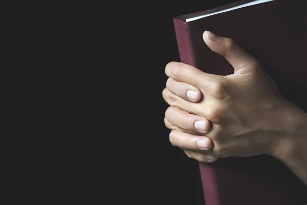 Hands folded in prayer on a Holy Bible  in church concept for faith, spirtuality and religion, Worship, sins and prayer.