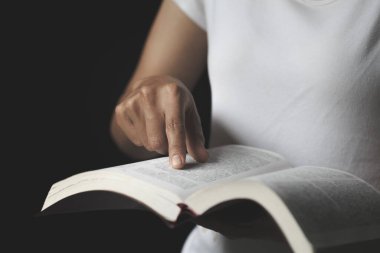 Kutsal kitabı işaret eden bir el ile okumak. İnançlı ve Hristiyan bir kadın dua ediyor. Fikirler, inançlar, dualar, arzular..