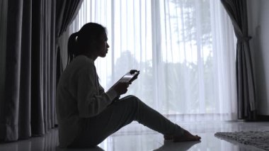 Yalnız genç kadının silueti depresyonda ve stresli hissediyor, karanlık odada el ele tutuşuyor, negatif duygular ve zihinsel sağlık kavramı..