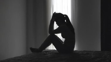 Yalnız genç kadının silueti depresyonda ve stresli hissediyor, karanlık odada el ele tutuşuyor, negatif duygular ve zihinsel sağlık kavramı..