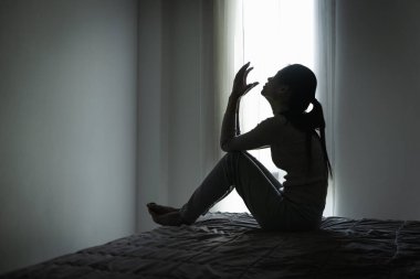 Genç Asyalı kadın evdeki kanepede oturuyor, üzgün, yorgun ve endişeli, akıl sağlığında depresyon geçiriyor. Depresyon, endişe ve uykusuzluk kavramında