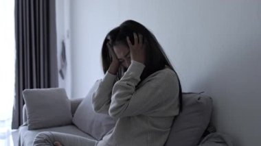 Genç Asyalı kadın evdeki kanepede oturuyor, üzgün, yorgun ve endişeli, akıl sağlığında depresyon geçiriyor. Depresyon, endişe ve uykusuzluk kavramında