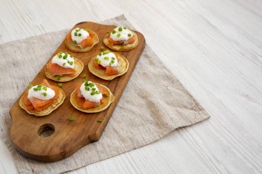 Tütsülenmiş somon, krema ve soğanlı ev yapımı Blini. Köy tahtasında, düşük açılı. Boşluğu kopyala.