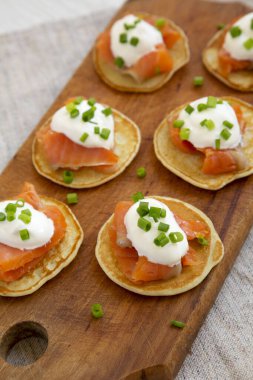 Tütsülenmiş somon, krema ve soğanlı ev yapımı Blini. Köy tahtasında, düşük açılı.. 