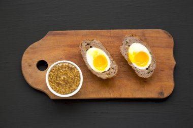 Ev yapımı İskoç yumurtaları siyah bir yüzey üzerinde ahşap bir tahta üzerinde, üst manzara. Dümdüz, tepeden, yukarıdan. 