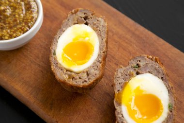 Ev yapımı İskoç yumurtaları, siyah arka planda, yakın planda, ahşap bir tahta üzerinde..