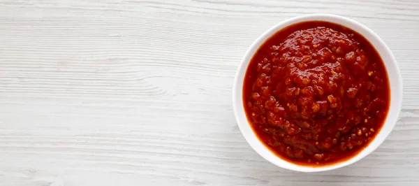 Homemade Tomato Salsa on a white wooden background, top view. Flat lay, overhead, from above. Copy space.