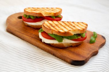 Tasty ızgara Caprese Panini (Mozzarella, Domatesler ve Basil) kırsal ahşap bir tahta üzerinde, yan görüş. 