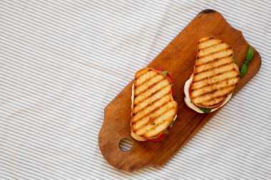 Tasty ızgara Caprese Panini (Mozzarella, Domatesler ve Basil) ahşap bir tahta üzerinde, tepeden görünür. Düz yatıyordu, üstten, yukarıdan. Boşluğu kopyala.