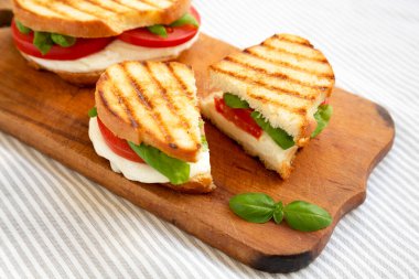 Tasty ızgara Caprese Panini (Mozzarella, Domatesler ve Basil) kırsal ahşap bir tahta üzerinde, düşük açılı görünüm.