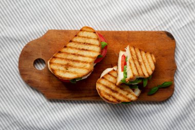 Tasty ızgara Caprese Panini (Mozzarella, Domates ve Basil), ahşap bir tahta üzerinde, üst manzara. Dümdüz, tepeden, yukarıdan. 