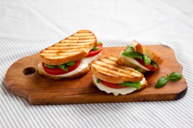 Tasty ızgara Caprese Panini (Mozzarella, Domatesler ve Basil) kırsal ahşap bir tahta üzerinde, yan görüş. 
