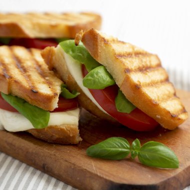 Tasty ızgara Caprese Panini (Mozzarella, Domates ve Basil), ahşap bir tahta üzerinde, yan görüş. Yakın plan..
