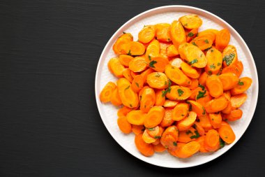 Siyah bir yüzey üzerinde tabakta ev yapımı Sauteed Havuç, üst manzara. Dümdüz, tepeden, yukarıdan. Metin için boşluk.
