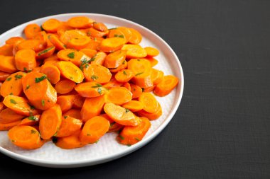 Siyah arka planda bir tabakta ev yapımı Sauteed Havuç, yan görüş. Boşluğu kopyala.